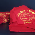 mehrere Waller-Cup Dobbrikow Shirts in rot mit gelber Aufschrift und Fisch