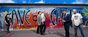 Menschen mit verschiedenen Textilien vor der Berliner Mauer